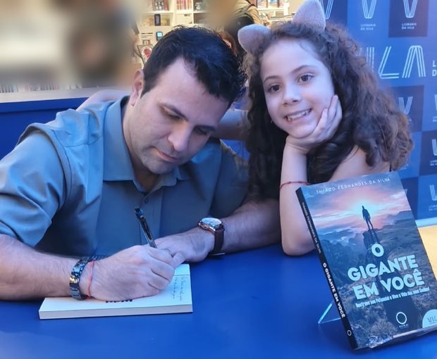 Thiago Fernandes autografando o livro O Gigante em Você ao lado da filha